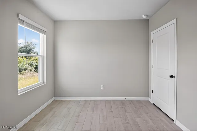 a view of an empty room with window and wooden floor