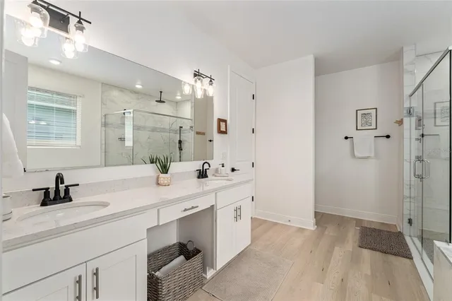 a bathroom with a double vanity sink a mirror a bathtub and shower