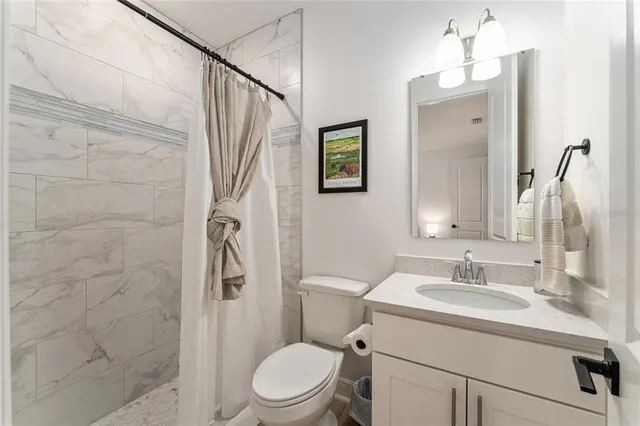 a bathroom with a sink a toilet a mirror and shower