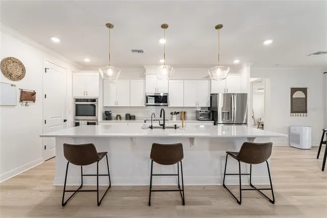 a kitchen with stainless steel appliances a dining table chairs sink and cabinets