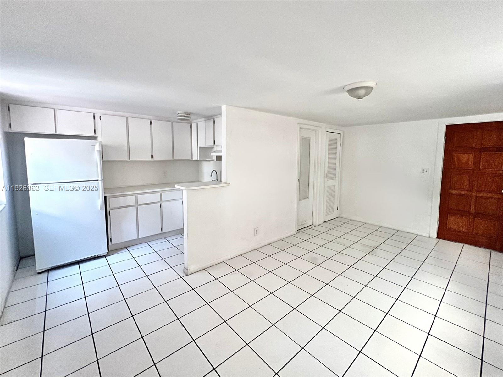 227 Phoenetia Avenue, Unit 3 Coral Gables, FL 33134 - Photo 2 of 10 a room with a white cabinet and a refrigerator