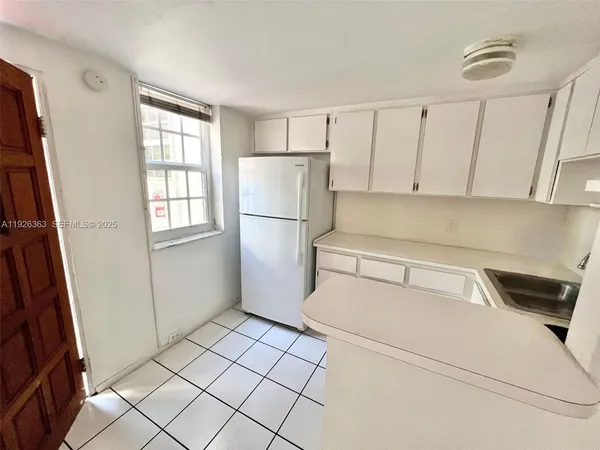 a kitchen with a refrigerator and white cabinets