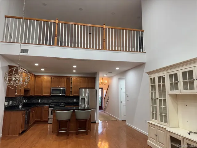 a open kitchen with stainless steel appliances kitchen island granite countertop a refrigerator a stove a sink and a dining table with wooden floor