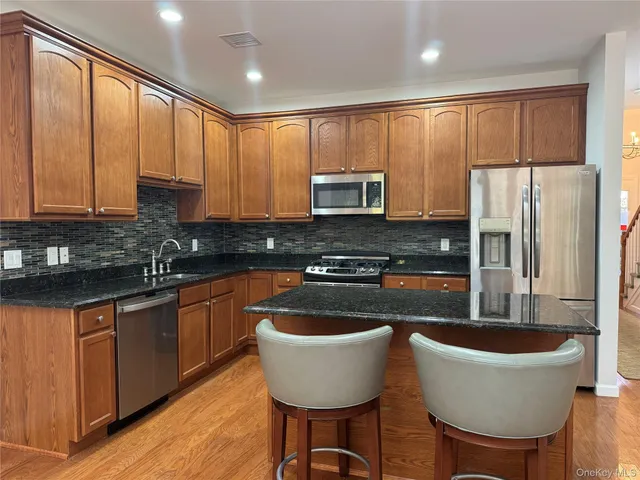 a kitchen with stainless steel appliances granite countertop a stove a sink a refrigerator a center island and a cabinets