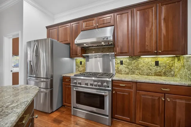 a bedroom with a bed a chair and potted plant on the dresser