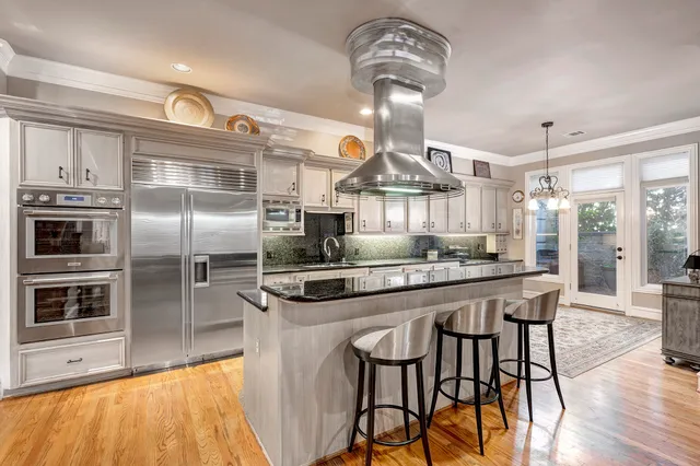 a kitchen with stainless steel appliances a dining table chairs stove and refrigerator