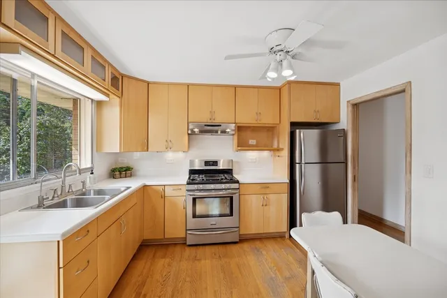 a kitchen with a sink a refrigerator a stove and white cabinets with wooden floor