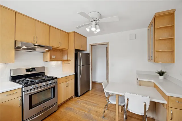 a kitchen with stainless steel appliances granite countertop a stove a sink dishwasher and a refrigerator with wooden floor