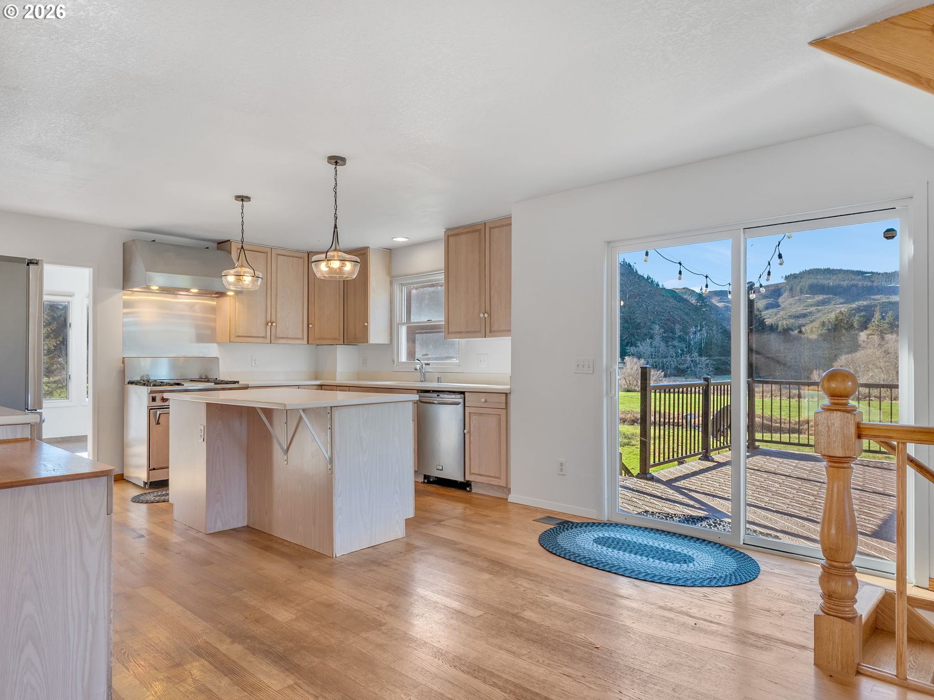 32300 Miami Foley Road Nehalem, OR 97131 - Photo 14 of 45 a kitchen with kitchen island granite countertop a stove a sink a refrigerator and white cabinets with wooden floor