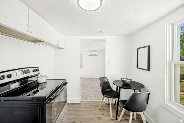 712 9th Street Ogden, UT 84404 - Photo 4 of 15 Kitchen area featuring white cabinetry, a black electric range, and wood-finish flooring