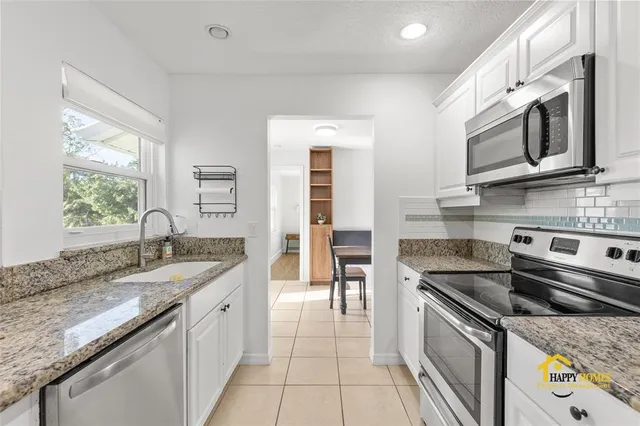 a kitchen with granite countertop white cabinets and white appliances