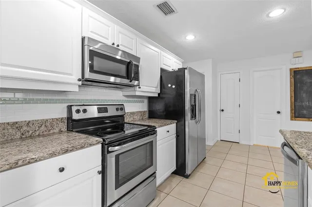a kitchen with stainless steel appliances granite countertop a refrigerator a stove and a sink