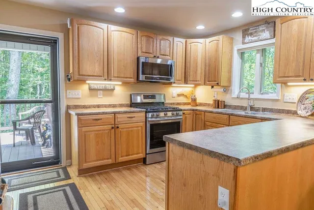 a kitchen with stainless steel appliances granite countertop a stove a sink and a microwave
