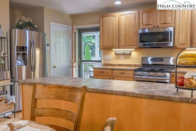 a kitchen with stainless steel appliances granite countertop a refrigerator a stove top oven a sink and dishwasher