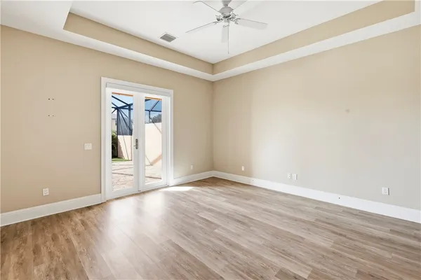 a view of an empty room with wooden floor and a ceiling fan