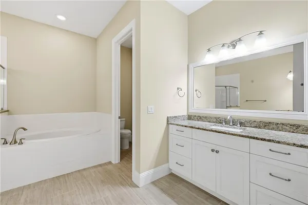 a bathroom with a granite countertop sink mirror and bathtub
