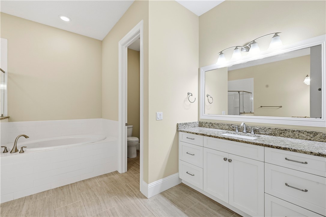 2030 Bridgepointe Circle, Unit 112 Vero Beach, FL 32967 - Photo 18 of 36 a bathroom with a granite countertop sink mirror and bathtub