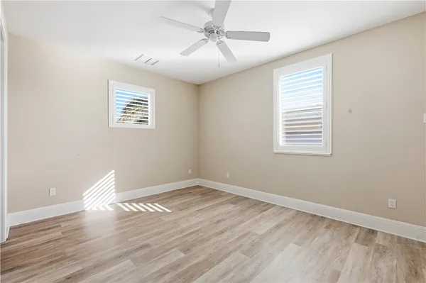 a view of empty room with wooden floor and fan