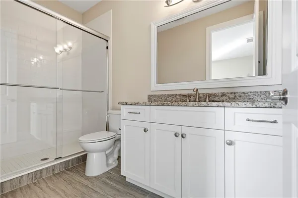 a bathroom with a granite countertop sink toilet a mirror and shower
