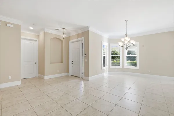 a view of an empty room with window and chandelier fan