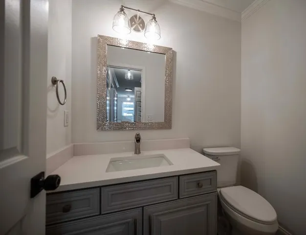 a bathroom with a sink vanity mirror and toilet