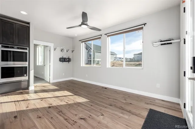 a view of empty room with wooden floor and fan