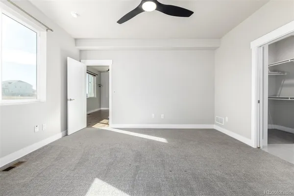 an empty room with fan and windows
