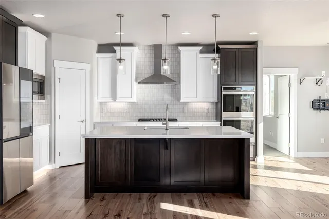 a kitchen with stainless steel appliances granite countertop a refrigerator a sink and a stove with wooden floors