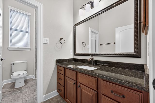 a bathroom with a granite countertop sink and a toilet