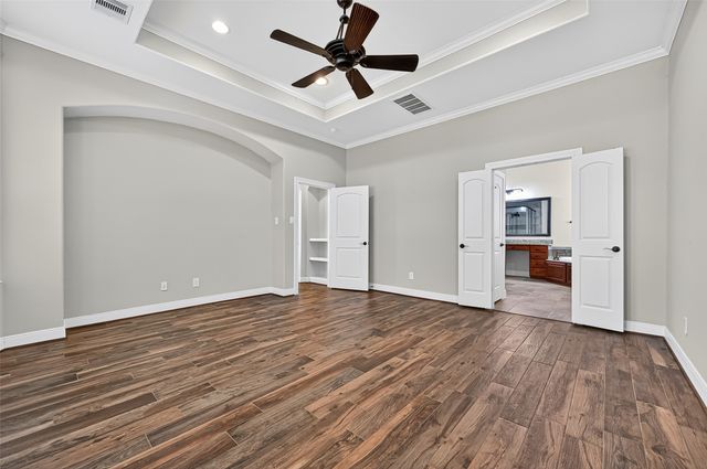 a view of empty room with wooden floor and ceiling fan