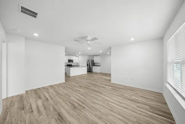 a view of an empty room with a window and wooden floor