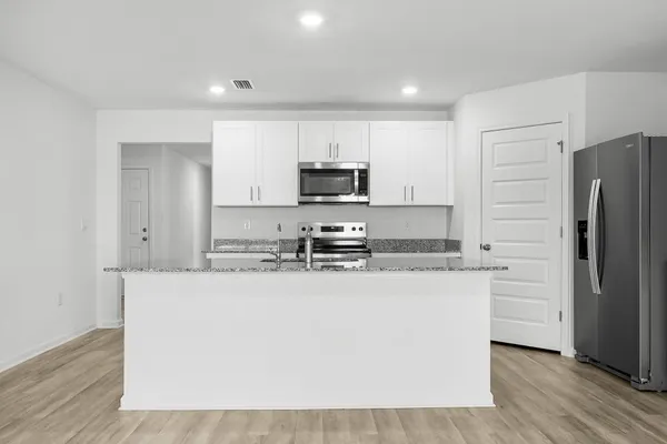 a kitchen with granite countertop a refrigerator and a stove top oven