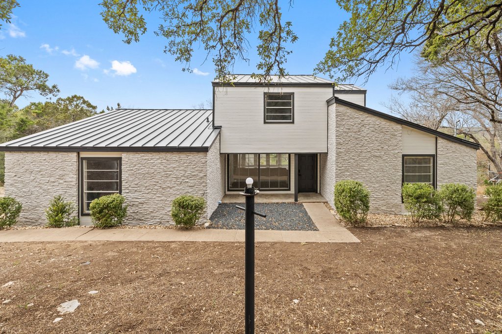 Back of house featuring a standing seam roof and stone siding