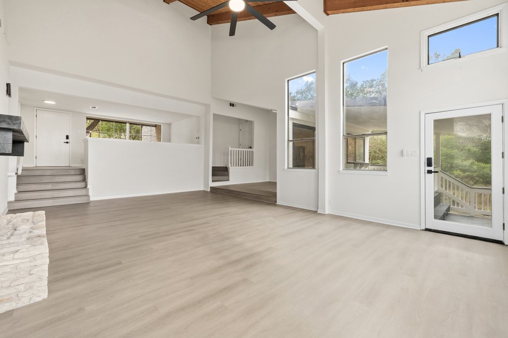 2204 Toro Canyon Road Austin, TX 78746 - Photo 8 of 26 Unfurnished living room featuring light wood-style floors, ceiling fan, and a high wood beamed ceiling