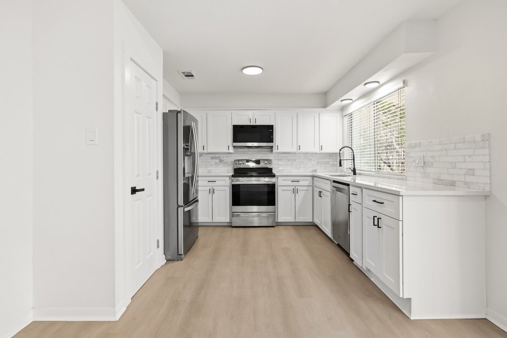 2204 Toro Canyon Road Austin, TX 78746 - Photo 10 of 26 Kitchen featuring stainless steel appliances, white cabinets, tasteful backsplash, and light wood-type flooring