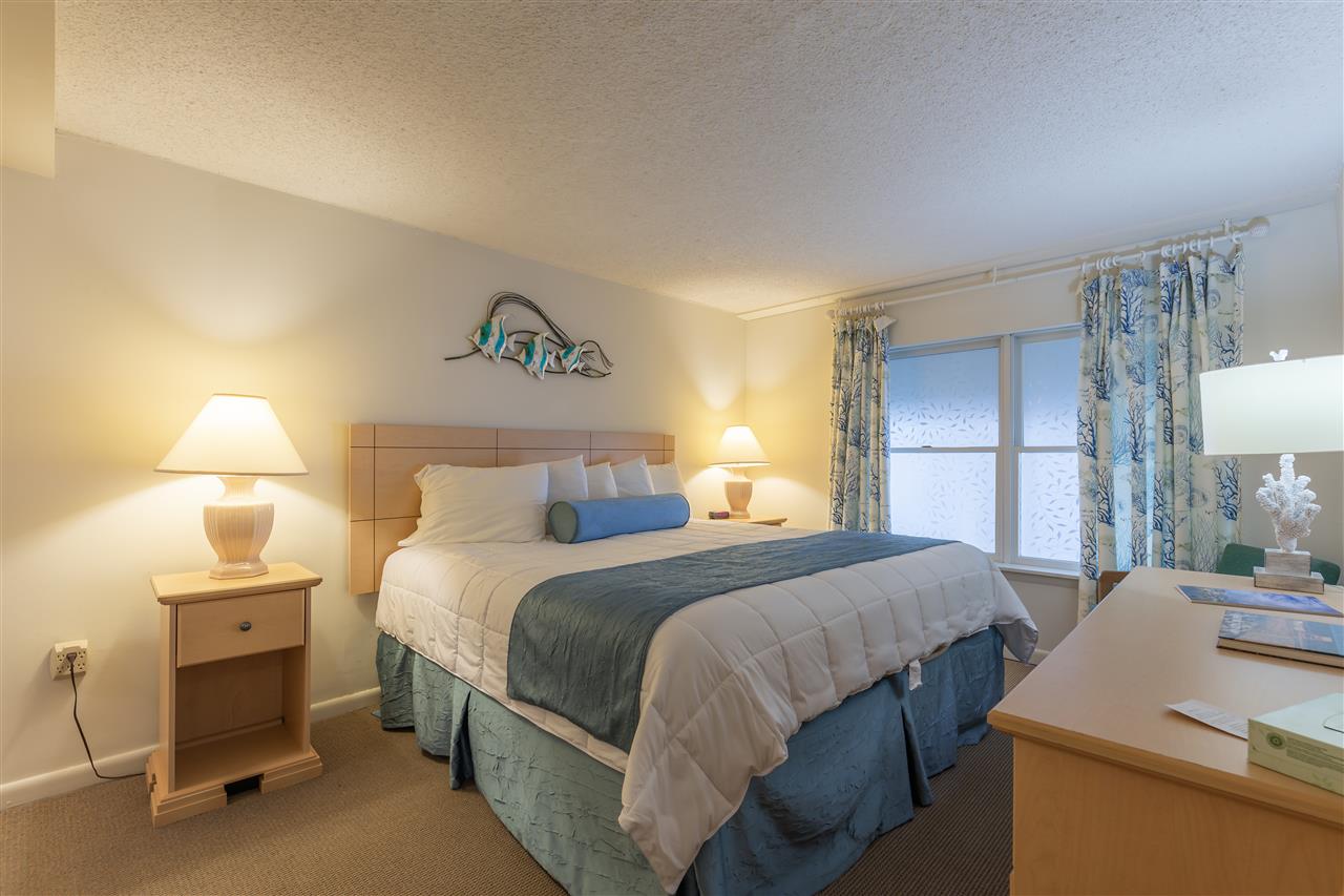 217 Beach, Unit 102 Cape May, NJ 08204 - Photo 18 of 30 a bedroom with a bed and a lamp on table