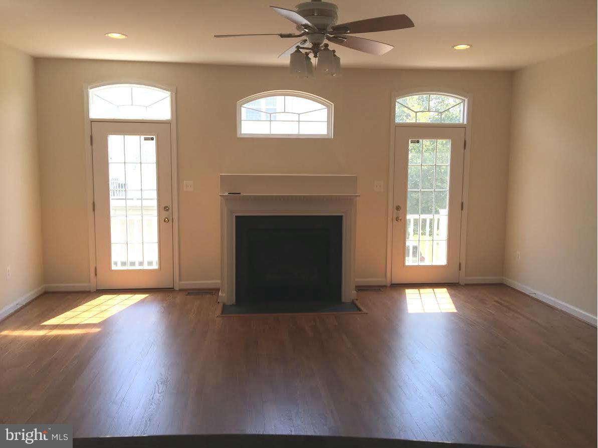 708 Redgate Lane Woodbridge, VA 22191 - Photo 4 of 20 an empty room with wooden floor fireplace and windows