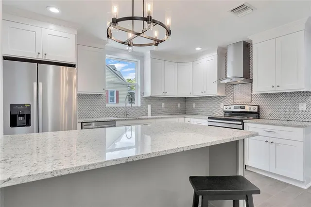 a kitchen with stainless steel appliances a sink a stove a refrigerator cabinets and wooden floor