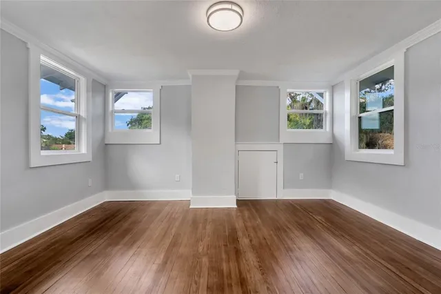 a view of empty room with wooden floor and window