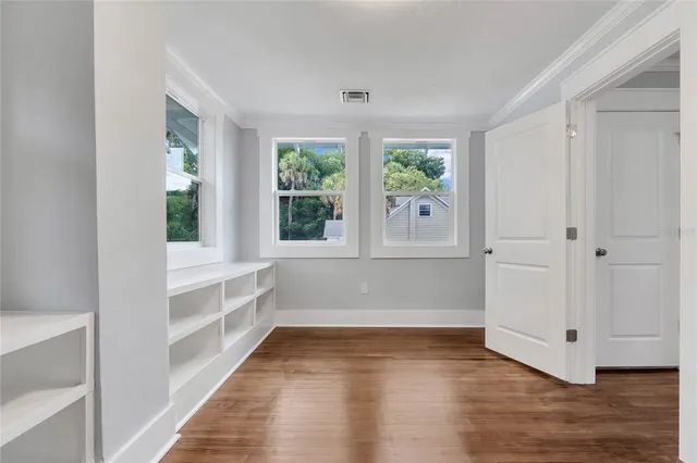 a view of an empty room with wooden floor and a window