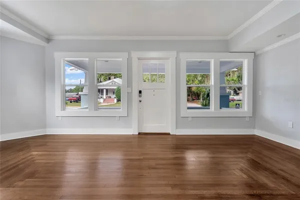 a view of an empty room with window and wooden floor