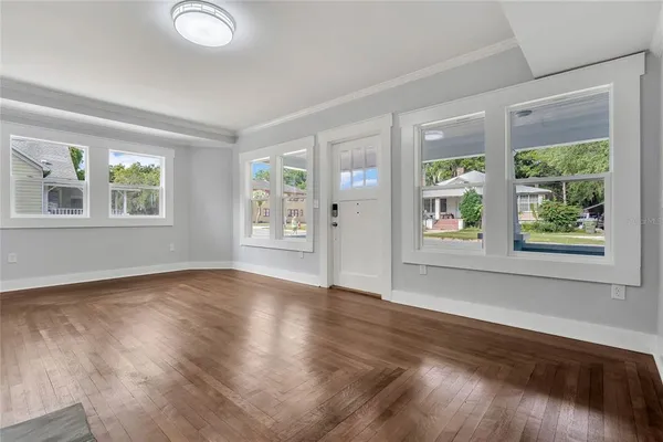 a view of an empty room with wooden floor and a window