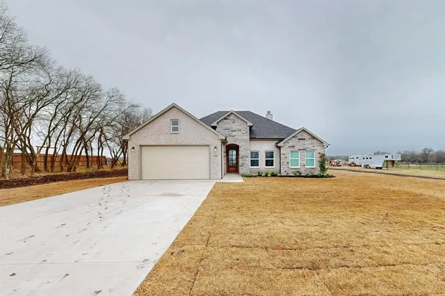 a front view of house along with trees in front of it