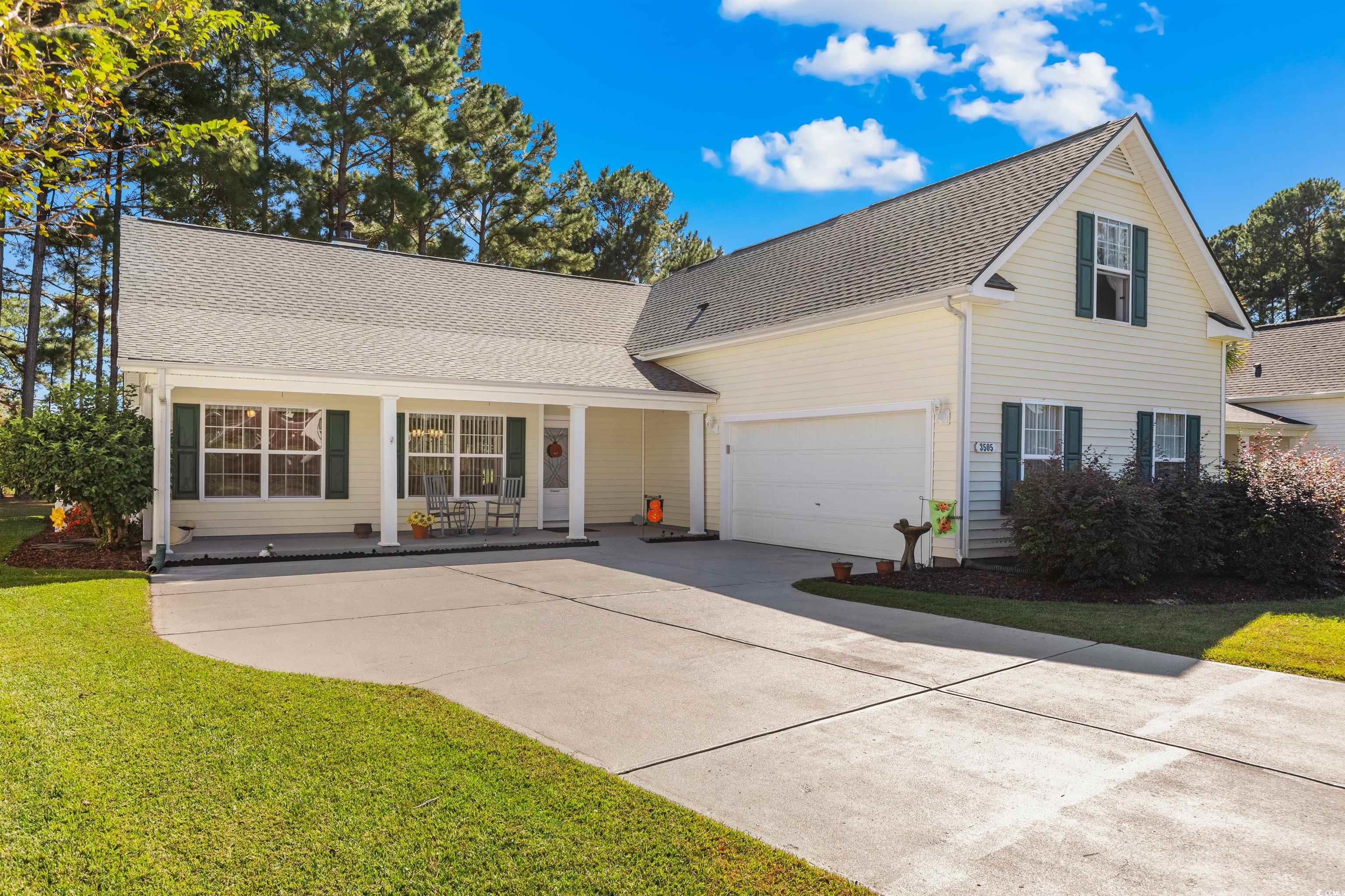 Traditional-style house with a porch, a shingled roof, a front lawn, and concrete driveway