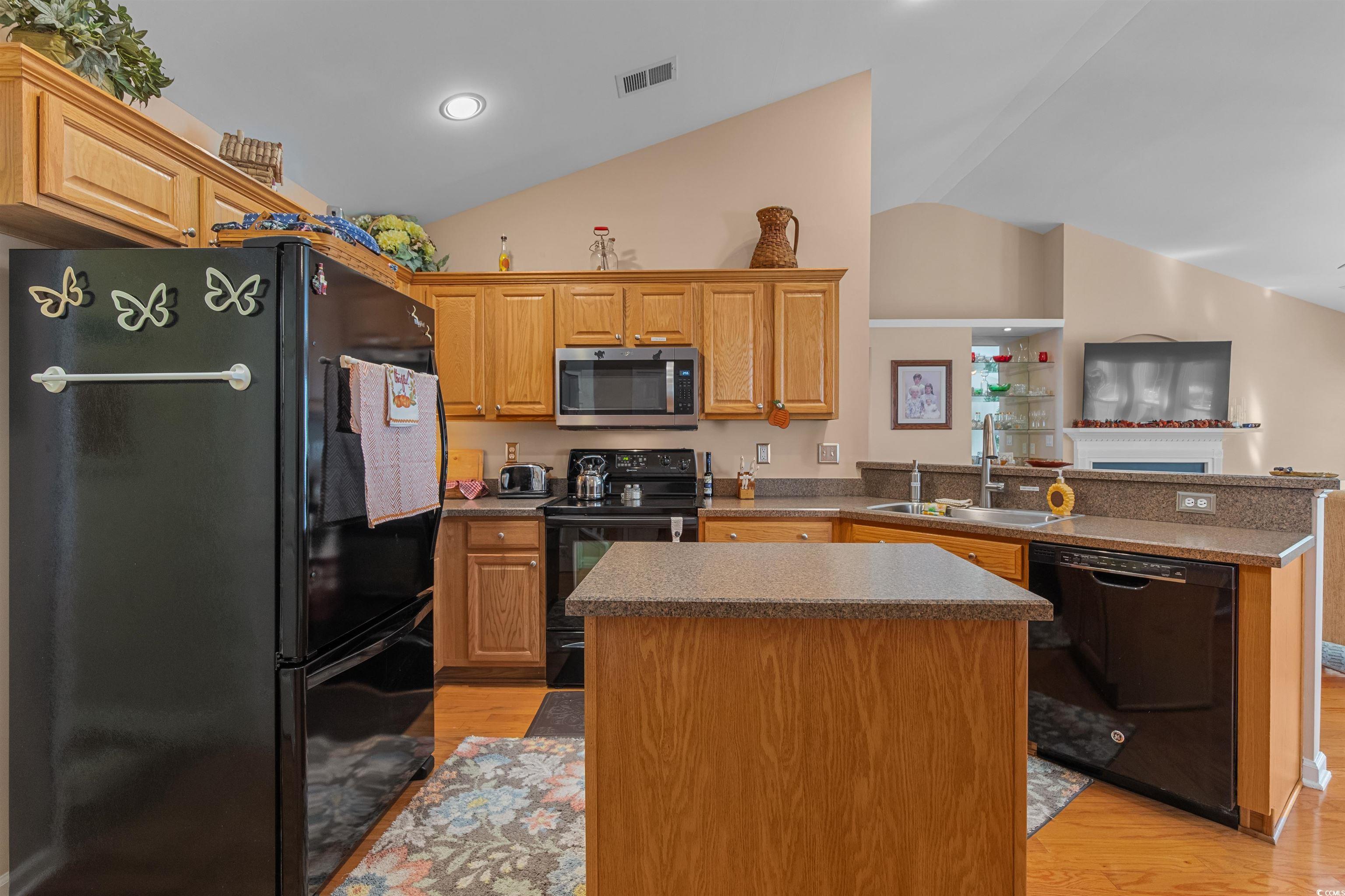 3505 Arrowhead Boulevard Myrtle Beach, SC 29579 - Photo 11 of 40 Kitchen with black appliances, a peninsula, light wood-type flooring, lofted ceiling, and a kitchen island