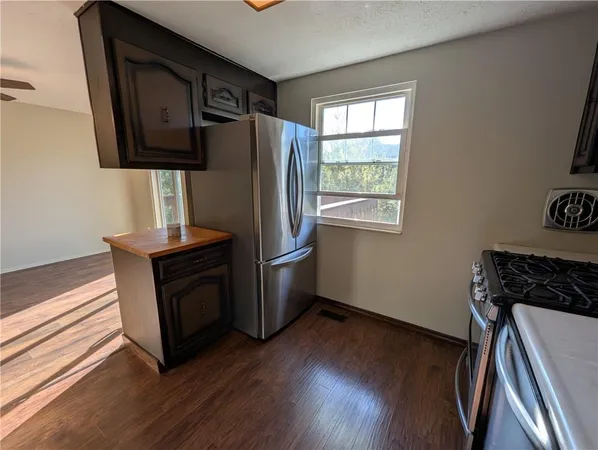 a kitchen with metallic refrigerator and wooden floor