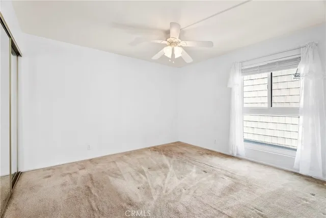 an empty room with windows and fan