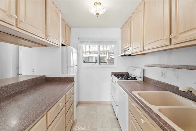 a kitchen with stainless steel appliances granite countertop a sink a stove and a refrigerator with white cabinets