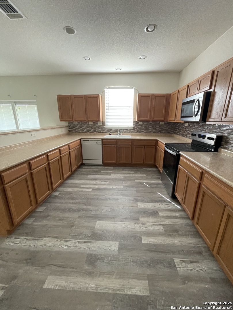 11111 Denae Drive Live Oak, TX 78233 - Photo 11 of 43 a large white kitchen with stainless steel appliances kitchen island granite countertop a sink and cabinets