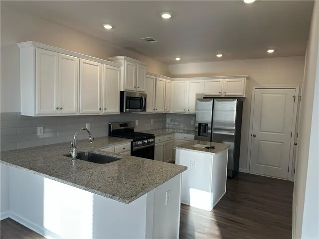 a kitchen with stainless steel appliances granite countertop a sink stove microwave and refrigerator
